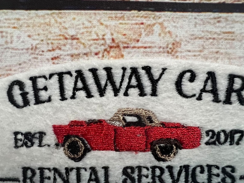 May include: Embroidered logo for a car rental business called "Getaway Car" established in 2017. The logo features a red convertible car with black wheels and a white top.