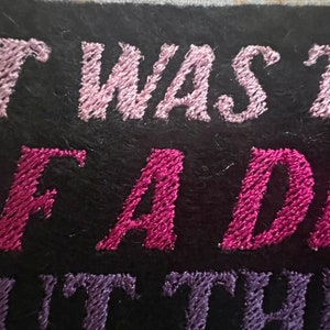 Puede incluir: Parche bordado con hilo rosa y morado. El texto dice "It was the best of a dea..."