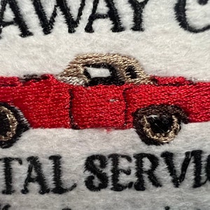 May include: Embroidered logo for a car rental service. The logo features a red convertible car with a tan top and the text "Stay Away Car Rental Service".
