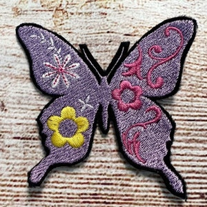 Peut inclure: Patch brodé de papillon violet avec des détails floraux roses et jaunes.