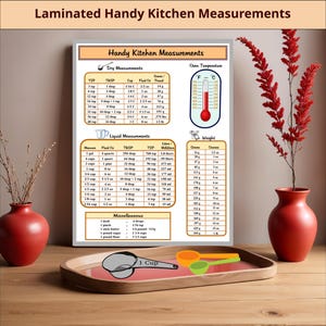 May include: A laminated kitchen conversion chart titled Handy Kitchen Measurements featuring tables for dry and liquid measurements, oven temperatures, and weights. The chart includes a graphic of a thermometer and measuring cups in orange and green.
