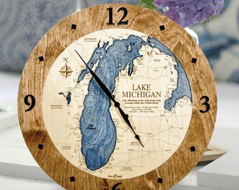 May include: A wooden clock with a map of Lake Michigan on the face. The clock has black hands and black numbers. The map is blue and brown and shows the surrounding states. The text on the map reads "Lake Michigan is the only Great Lake entirely within the United States".