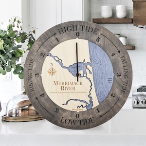 May include: A wooden tide clock with a map of the Merrimack River, featuring the towns of Salisbury Beach, Newburyport, and Plum Island. The clock face has a dark brown background with white numbers and arrows indicating high and low tide.