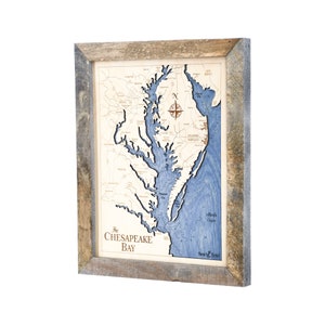 May include: A framed wooden map of the Chesapeake Bay, featuring a detailed depiction of the bay's waterways in blue and beige tones. The map includes the text "The Chesapeake Bay" and a compass rose. The frame is made of weathered wood.