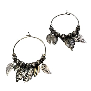 May include: A pair of silver-toned hoop earrings featuring a series of small, ribbed spherical beads along the bottom curve. Each hoop is adorned with multiple dangling metal leaf charms that have detailed, etched vein patterns on their surfaces.