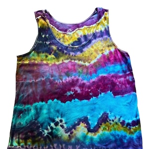 May include: A tie-dye tank top in shades of purple, blue, yellow, and pink. The sleeveless top has a scoop neck and a relaxed fit. The fabric appears soft and lightweight, ideal for warm weather. The top has a small tag near the neckline.