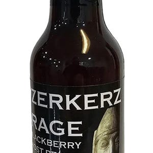 May include: A dark glass bottle of Zerkerz Rage Blackberry Ghost Pepper sauce. The label features text and an illustration of a face. The ingredients include blackberries, lime juice, and ghost peppers.