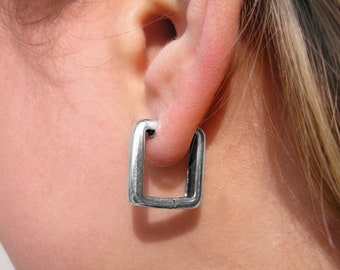 May include: A pair of silver square hoop earrings. The earrings are simple and modern in design.