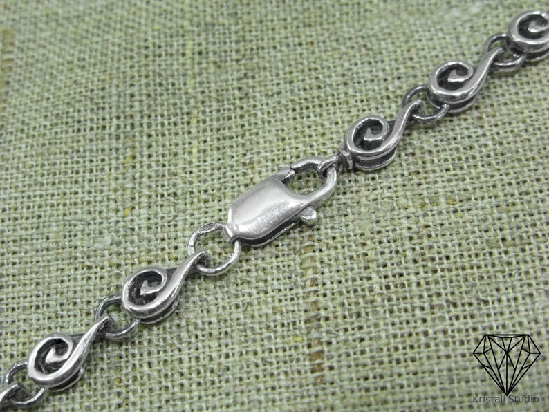 May include: A silver chain necklace with a clasp closure. The chain is made of small, linked, spiral-shaped pieces.