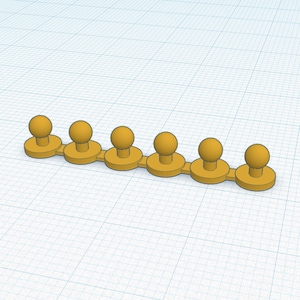 May include: A row of seven gold-colored plastic push pins with round heads.