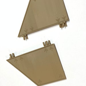 Könnte beinhalten: Zwei braune Plastikteile mit Pfeilmarkierungen. Die Teile sind trapezförmig mit einer spitzen Spitze.