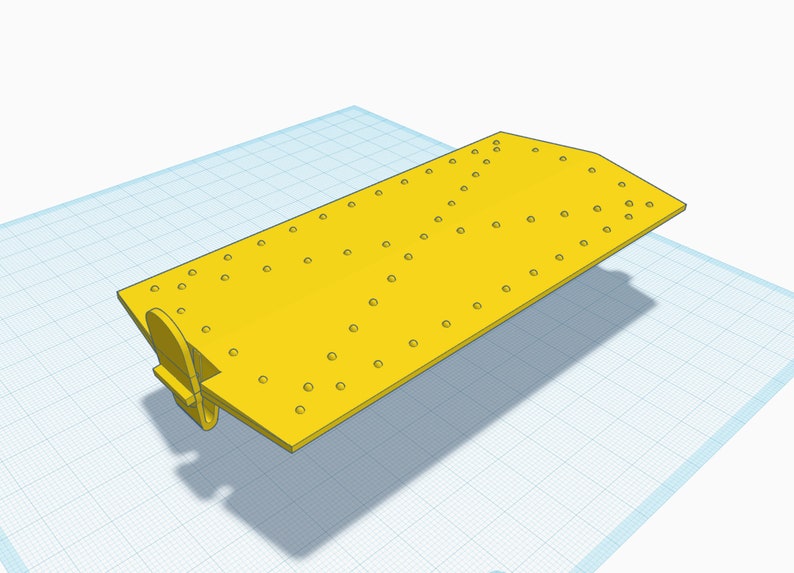 May include: A yellow plastic plate with a grid of holes. The plate has a small yellow plastic tab on the side.