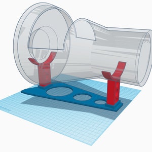 Pode incluir: Um suporte impresso em 3D com dois suportes vermelhos para uma roda e um tubo de hamster de plástico transparente. O suporte tem uma base azul com três recortes circulares.