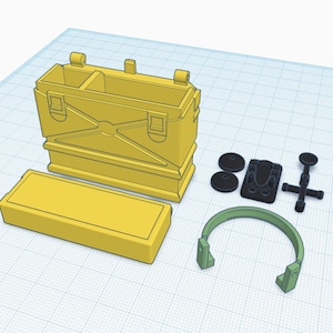 Puede incluir: Un conjunto de equipo militar de juguete de plástico amarillo, que incluye una caja con tapa abatible, una caja más pequeña, un auricular y una pequeña pieza de plástico negro con asa.