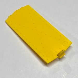 May include: A yellow plastic track piece with a textured surface and a small connector on one end.