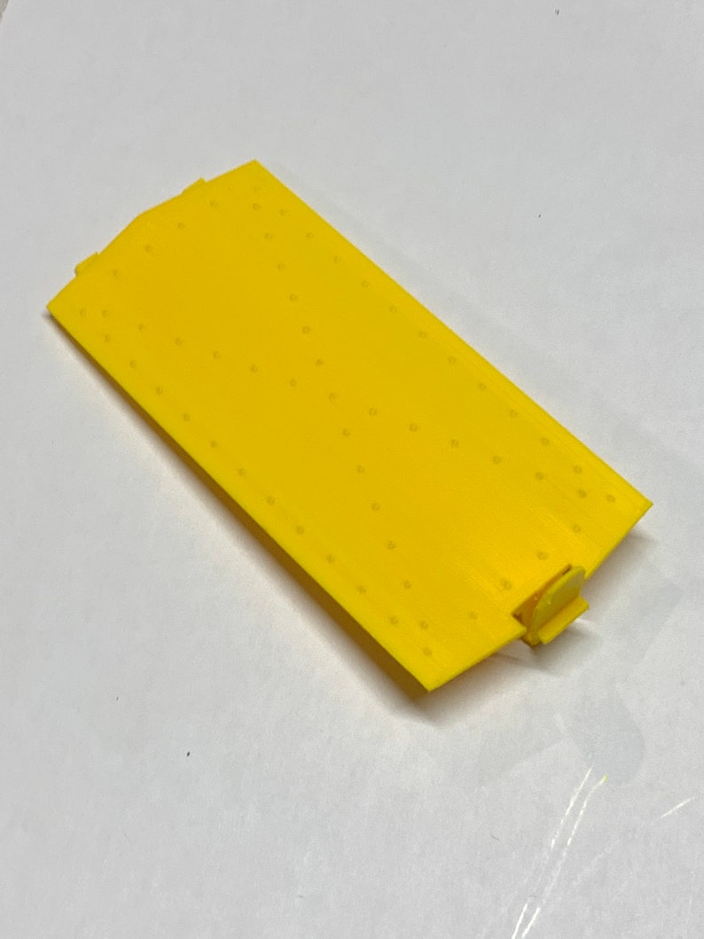 May include: A yellow plastic track piece with a textured surface and a small connector on one end.