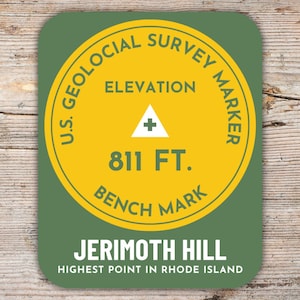 Könnte beinhalten: Ein runder Aufkleber in Grün und Gelb mit dem Text "U.S. Geological Survey Marker" und "Elevation 811 FT. Bench Mark". Der Aufkleber trägt außerdem den Text "Jerimoth Hill Highest Point in Rhode Island".