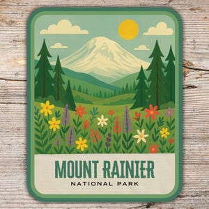 May include: A rectangular sticker with a landscape illustration of Mount Rainier National Park. The design features a snow-covered mountain, green trees, wildflowers, a yellow sun, and the text "MOUNT RAINIER NATIONAL PARK."