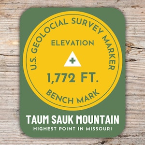 Könnte beinhalten: Ein runder Aufkleber in Grün und Gelb mit dem Text "U.S. Geological Survey Marker" und "Elevation 1,772 FT. Bench Mark". Der Aufkleber trägt außerdem den Text "Taum Sauk Mountain Highest Point in Missouri".