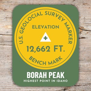 Könnte beinhalten: Ein runder Aufkleber in Grün und Gelb mit dem Text "U.S. Geological Survey Marker" und "Elevation 12,662 FT. Bench Mark". Der Aufkleber trägt außerdem den Text "Borah Peak Highest Point in Idaho".