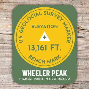 Könnte beinhalten: Ein runder Aufkleber in Grün und Gelb mit dem Text "U.S. Geological Survey Marker" und "Elevation 13,161 FT. Bench Mark". Der Aufkleber trägt außerdem den Text "Wheeler Peak" und "Highest Point in New Mexico".