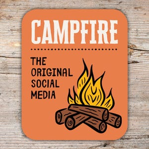 May include: Orange square coaster with the word "CAMPFIRE" in white, above the text "THE ORIGINAL SOCIAL MEDIA." A graphic of a campfire with flames and logs is below the text. The coaster is on a wooden surface.