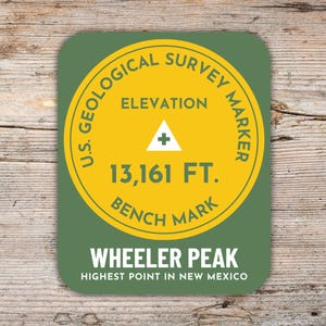May include: A rectangular sticker with rounded corners featuring a yellow circle on a green background. The text reads U.S. GEOLOGICAL SURVEY MARKER, ELEVATION 13,161 FT. BENCH MARK, WHEELER PEAK, and HIGHEST POINT IN NEW MEXICO with a triangle symbol.