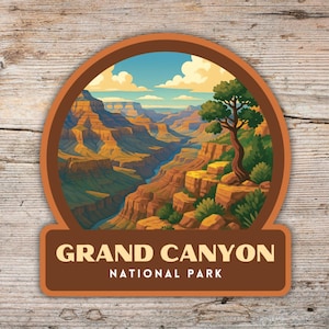 May include: A round sticker featuring a scenic illustration of the Grand Canyon National Park. The image shows the canyon's layered rock formations, a river, and a tree. The sticker has a brown border and the text "GRAND CANYON NATIONAL PARK".