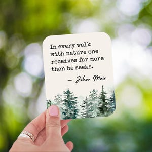 May include: A white card with a quote by John Muir about nature. The quote reads: "In every walk with nature one receives far more than he seeks." The card has a watercolor illustration of a forest.