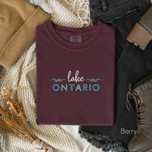 May include: A maroon t-shirt with the text "lake ONTARIO" in blue and green lettering with wavy lines above and below the text.