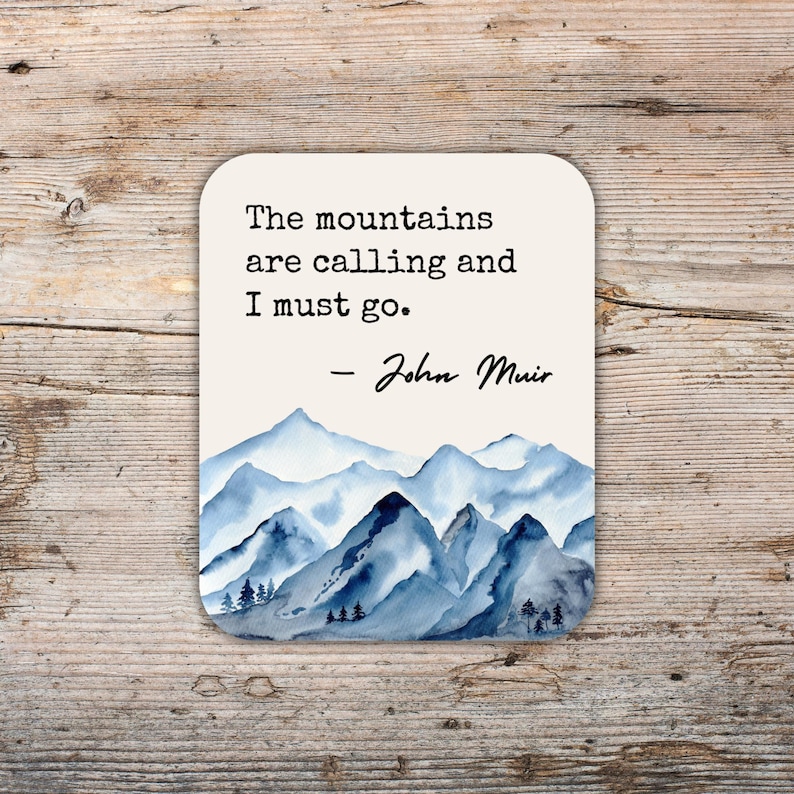 K&ouml;nnte beinhalten: Ein wei&szlig;er Untersetzer mit einer blauen Aquarell-Berglandschaft und dem Zitat "The mountains are calling and I must go. - John Muir".