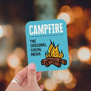 May include: A light blue square sticker with rounded corners, featuring the word "CAMPFIRE" in white, above the text "THE ORIGINAL SOCIAL MEDIA." A graphic of a campfire with flames and logs is below the text.