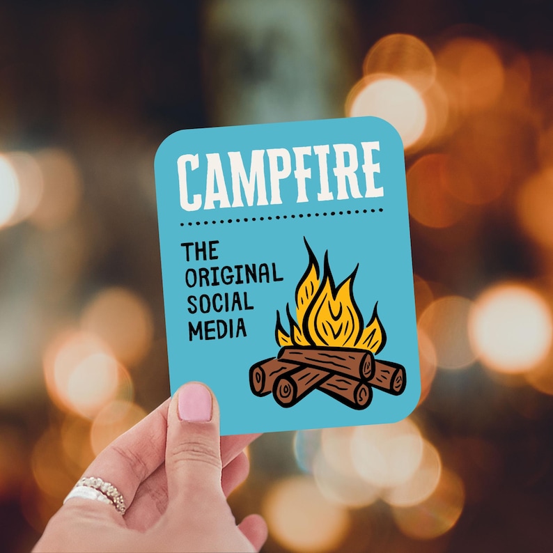 May include: A light blue square sticker with rounded corners, featuring the word "CAMPFIRE" in white, above the text "THE ORIGINAL SOCIAL MEDIA." A graphic of a campfire with flames and logs is below the text.
