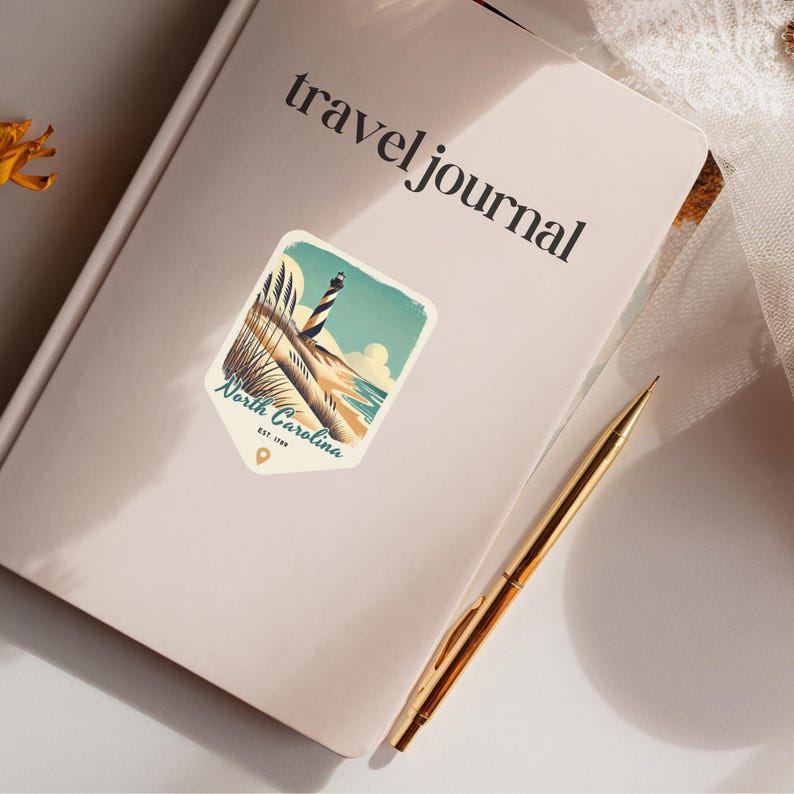 May include: A travel journal with a sticker of a lighthouse on a beach with the text "North Carolina Est. 1789" on it.