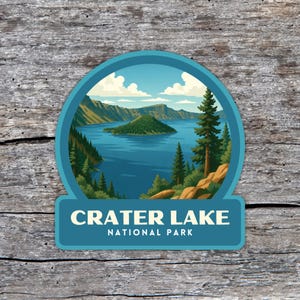 May include: A round sticker featuring a scenic view of Crater Lake National Park. The image shows a blue lake surrounded by green trees and mountains under a blue sky with clouds. The text "CRATER LAKE NATIONAL PARK" is displayed at the bottom.