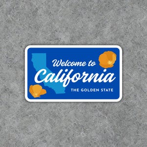 May include: A rectangular sticker with a blue background and white border. The sticker features the text "Welcome to California" and "California" in white script, along with a light blue outline of the state and two orange California poppies. The text "THE GOLDEN STATE" is also included.