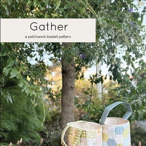 May include: Two patchwork fabric baskets with handles, one green and blue, the other pink and green, sitting on a wooden table in a garden setting. The text "Gather, a patchwork basket pattern" is displayed above the baskets.