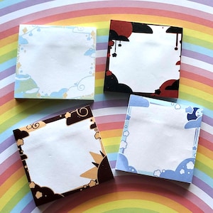 Può includere: Quattro blocchi di note quadrati con bordi decorativi. Ogni nota ha un centro bianco per la scrittura. I bordi presentano disegni di nuvole, soli ed elementi celesti in colori come blu, marrone, rosso e nero. Lo sfondo è un arcobaleno.