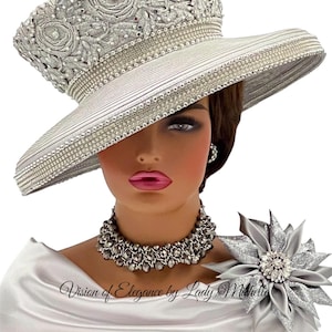 May include: A silver wide-brimmed hat featuring intricate floral embroidery, rhinestone bands, and a matching silver fabric flower brooch with a crystal center. The text Vision of Elegance by Lady Michelle is printed across the lower section.