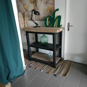 Peut inclure: Une étagère en bois noir avec deux étagères et une surface supérieure. L'étagère est décorée d'une bouteille en verre vert et d'une pancarte verte qui dit "oh".