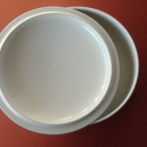 May include: A white ceramic bowl with a lid. The bowl is round and has a smooth, glossy finish.