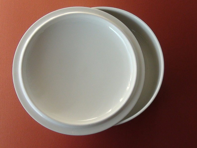 May include: A white ceramic bowl with a lid. The bowl is round and has a smooth, glossy finish.