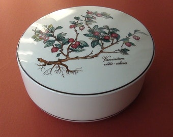 May include: White ceramic lidded box with a botanical illustration of a plant with green leaves and red berries. The text "Vaccinium vitis-idaea" is printed on the box.