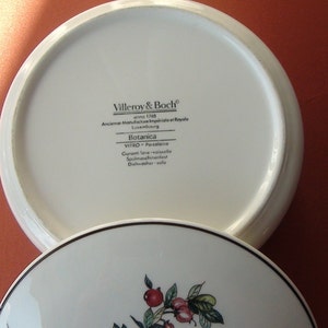 May include: White porcelain lid with black text that reads "Villeroy & Boch, anno 1748, Anciense Manufacture Imp&eacute;riale et Royale, Luxembourg, Botanica, VITRO - Porcelaine, Garanti love vaisselle, Spulmaschinenfest, Dishwasher safe".