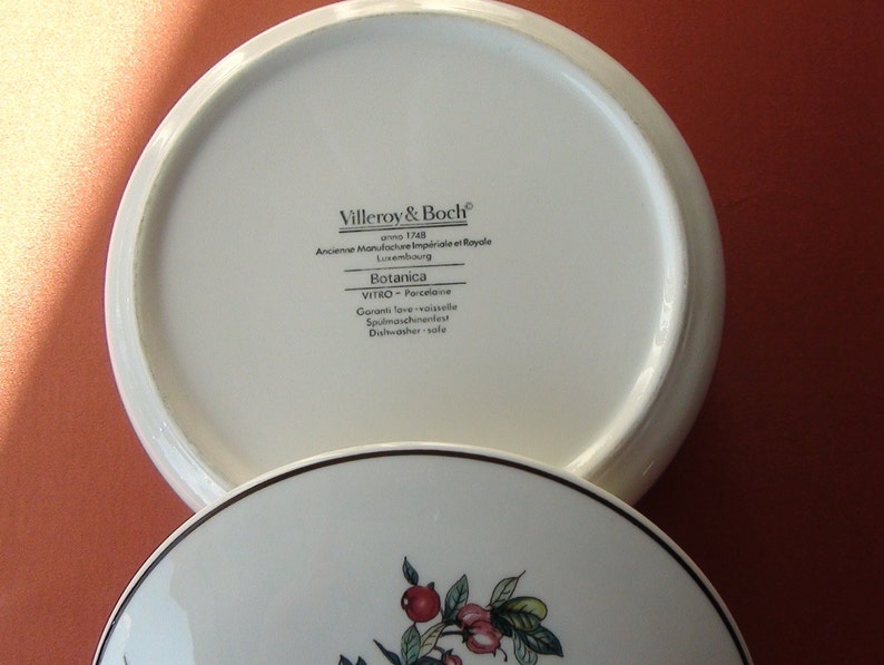 May include: White porcelain lid with black text that reads "Villeroy & Boch, anno 1748, Anciense Manufacture Imp&eacute;riale et Royale, Luxembourg, Botanica, VITRO - Porcelaine, Garanti love vaisselle, Spulmaschinenfest, Dishwasher safe".