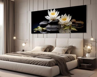 May include: A black and white photograph of two white water lilies with yellow centers on a bed of smooth black stones. The lilies are reflected in the water.