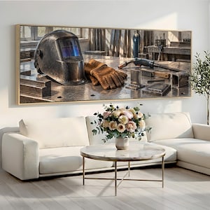 Peut inclure: Une impression murale rectangulaire représentant un casque de soudage métallique sombre, une paire de gants de travail en cuir beige, un chalumeau et une brosse métallique posés sur un établi en métal dans un atelier avec des pièces en acier.