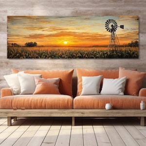 Peut inclure: Une œuvre d'art rectangulaire représente un coucher de soleil rural. L'œuvre présente une silhouette de moulin à vent sur un ciel orange et jaune, au-dessus d'un champ de cultures. L'œuvre est au-dessus d'un canapé orange avec des coussins blancs.