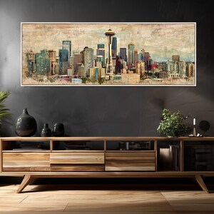 May include: A framed panoramic print of the Seattle skyline, featuring the Space Needle and various skyscrapers. The artwork has a vintage, textured appearance with muted colors, including blues, browns, and greens. The print is displayed above a wooden media console.
