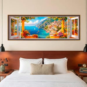 Puede incluir: Una impresión artística enmarcada que representa una vibrante escena costera. La obra de arte muestra una ventana abierta con vistas a un colorido pueblo italiano, con barcos en el mar turquesa. El marco de la ventana tiene contraventanas blancas y flores naranjas.